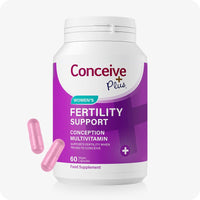 Conceive Plus Fertility Supplement For Women, showing a white and purple bottle labeled “Fertility Support Conception Multivitamin” with two pink vegan capsules displayed in front, designed to support women’s fertility and reproductive health.
